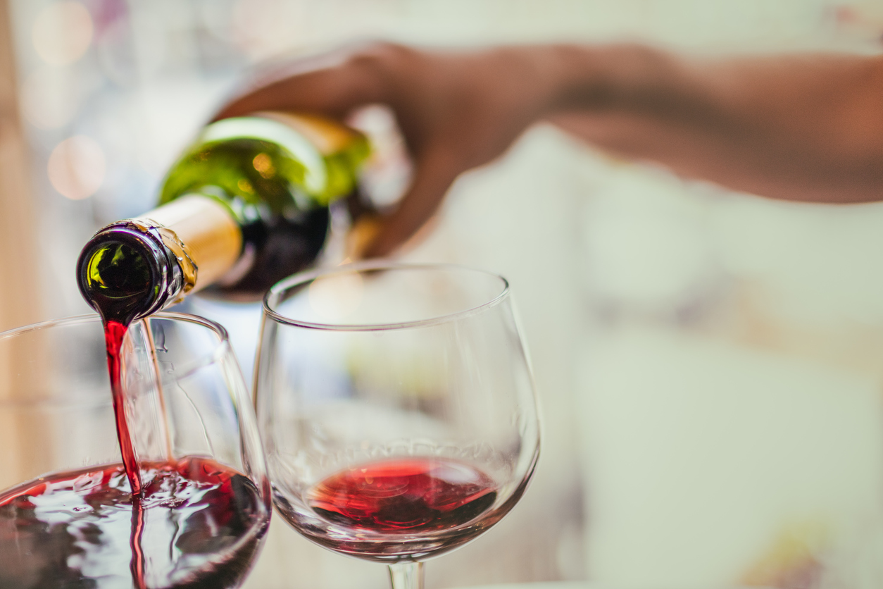 Unrecognizable man pouring red wine in two glasses.