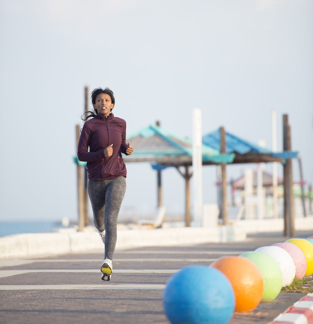 Healthy lifestyle and running sprinting fast. Woman in shape training outdoors on the seafront of the beach.