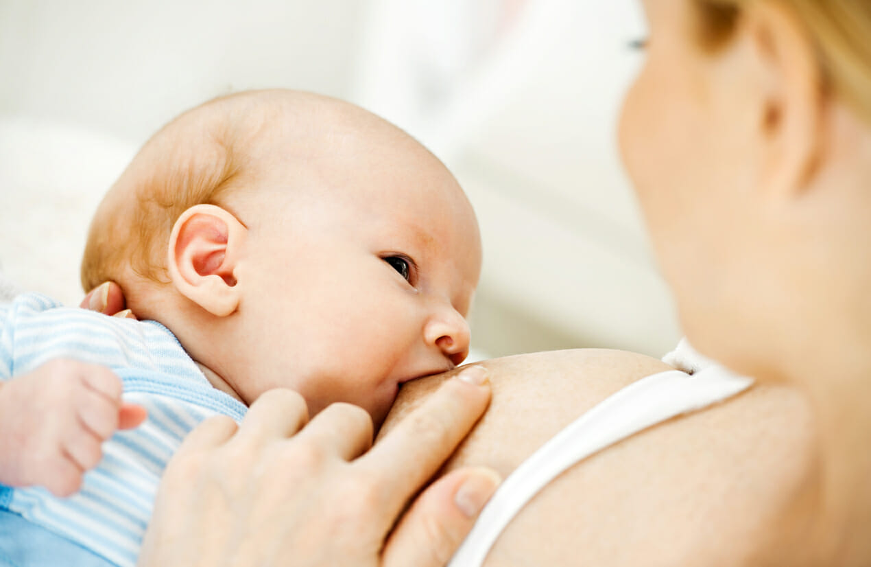 A cute newborn baby boy breastfeeding.