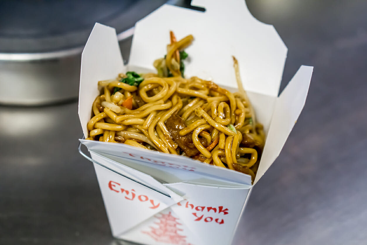 chinese lo mein in a take out box on a restraurant table