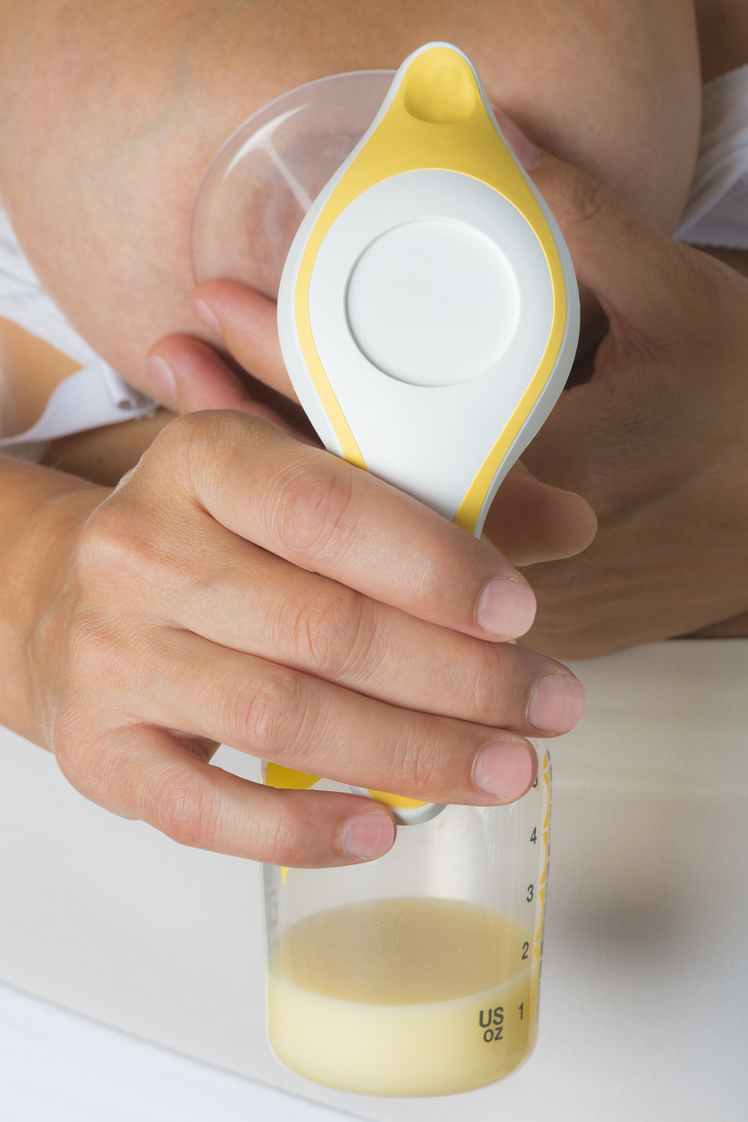 Mother getting milk with a manual breast pump isolated on a white background
